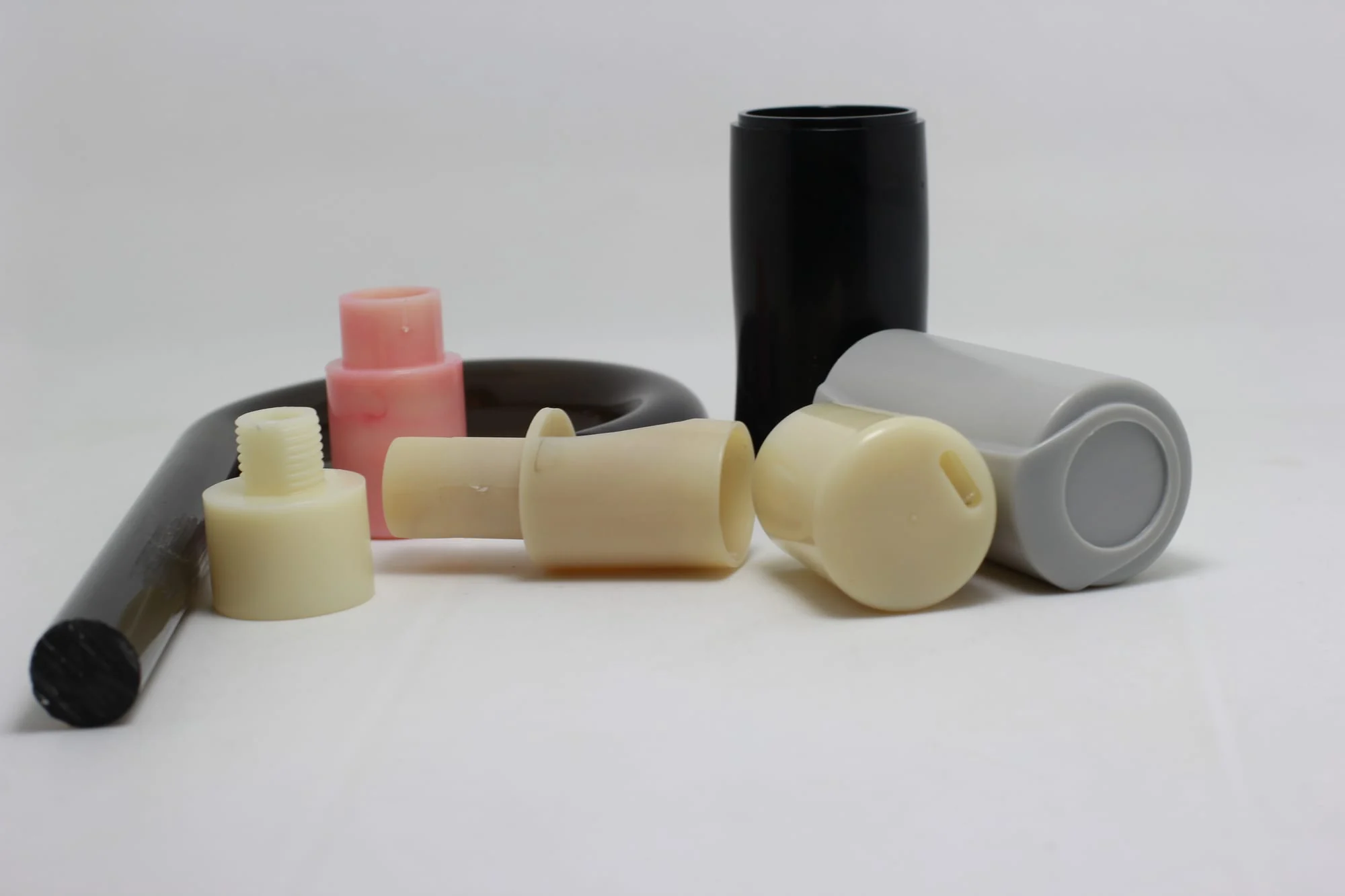 The image shows a white table with a variety of different types of plastic bottles, including a lip balm tube, a lip gloss tube, and a lip liner tube, all of which are part of a wholesale plastic tube