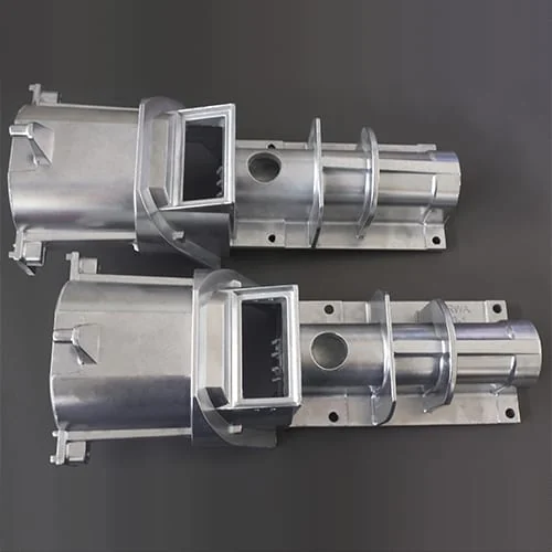 The image shows a pair of metal parts on a gray background, which appear to be part of a CNC milling machine. The metal parts are silver in color and have a glossy finish.