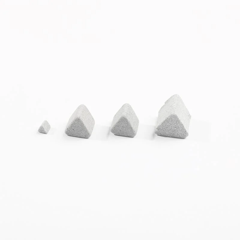 The image shows a set of four grey concrete pyramids on a white background. The pyramids are arranged in a triangular formation, with the largest one in the center and two smaller ones on either side.