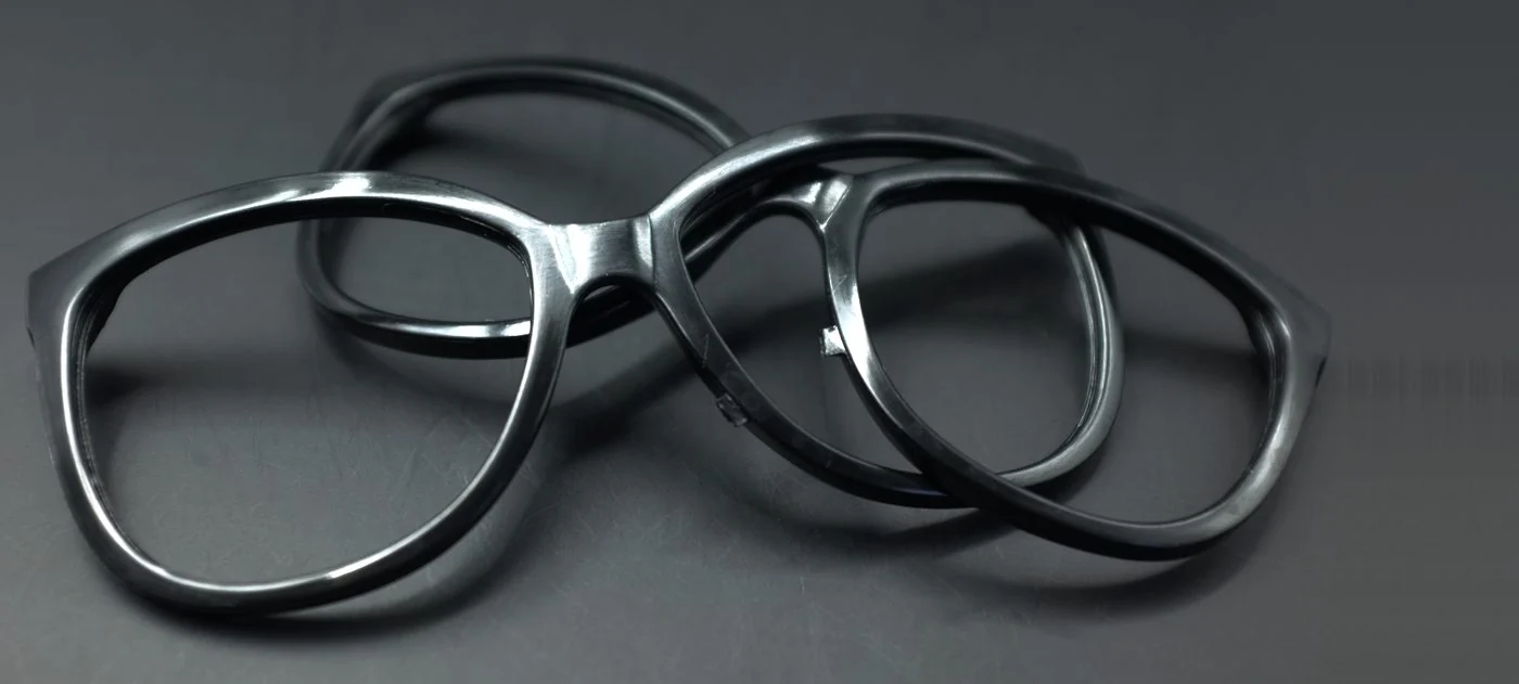 Real polished black plastic eyeglass frames showing smooth glossy surface finish