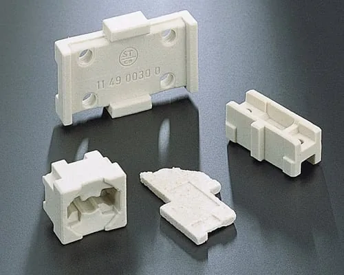 The image shows a set of three white plastic connectors on a black surface. The connectors are arranged in a triangular formation, with the largest connector in the center and two smaller connectors o